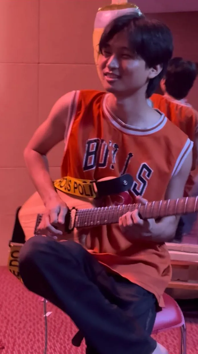 A smiling player in red light plays Solic Arc on a stool.