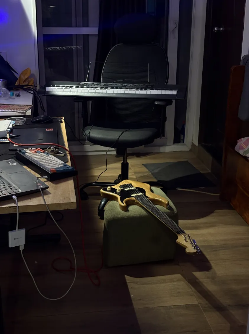 Solic Arc resting on a stool at night in a room with a keyboard and desk.