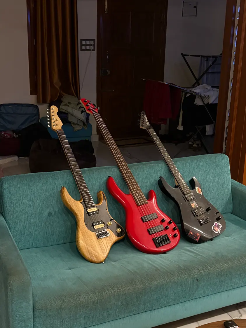 Solic Arc standing on a sofa beside a red bass and a black Jackson.