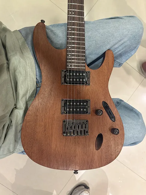 Top-down view of a mahogany super-Strat resting on the thigh.