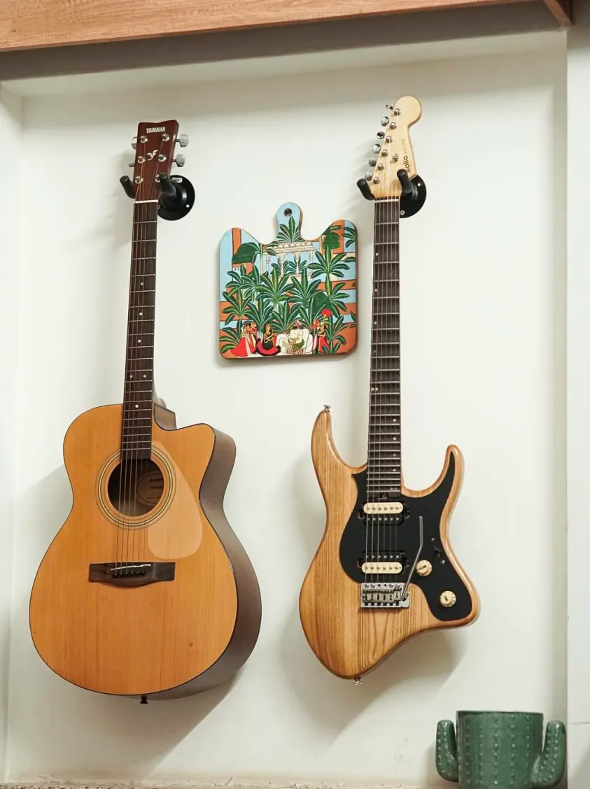 Solic Arc hanging on a white wall beside an acoustic guitar.